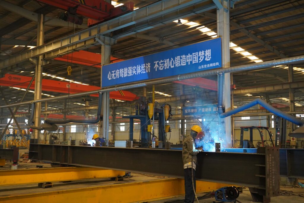 A certified welder is performing welding work in a steel-structure workshop.