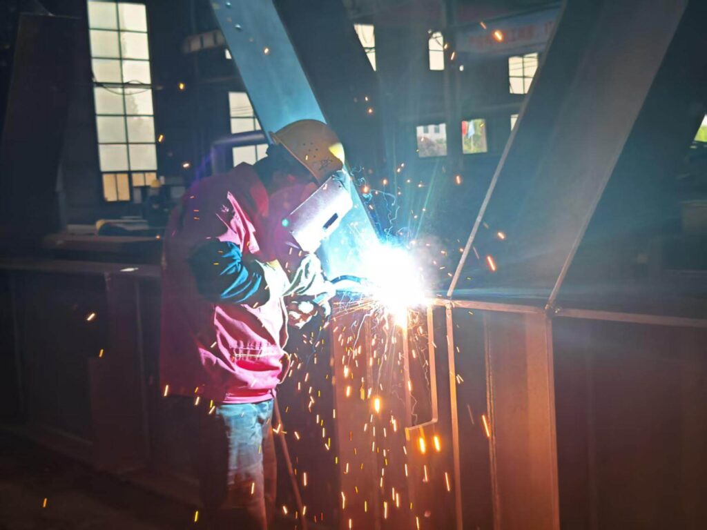 Workers in the SynJect production workshop are welding steel structures.