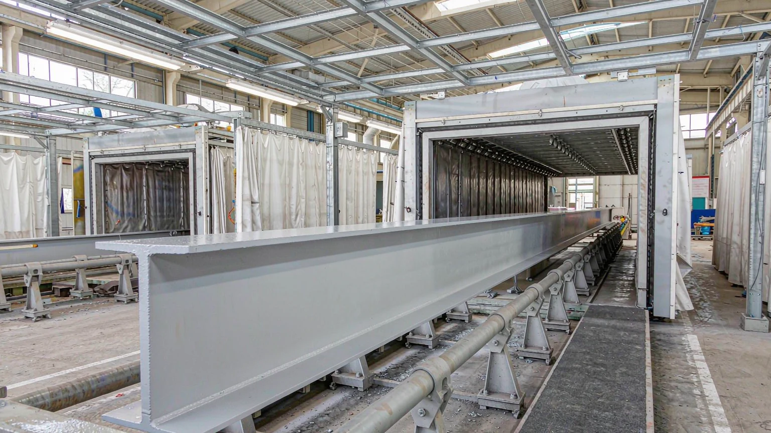 Blast-cleaned built-up H-section entering the coating booth on an automated surface preparation line
